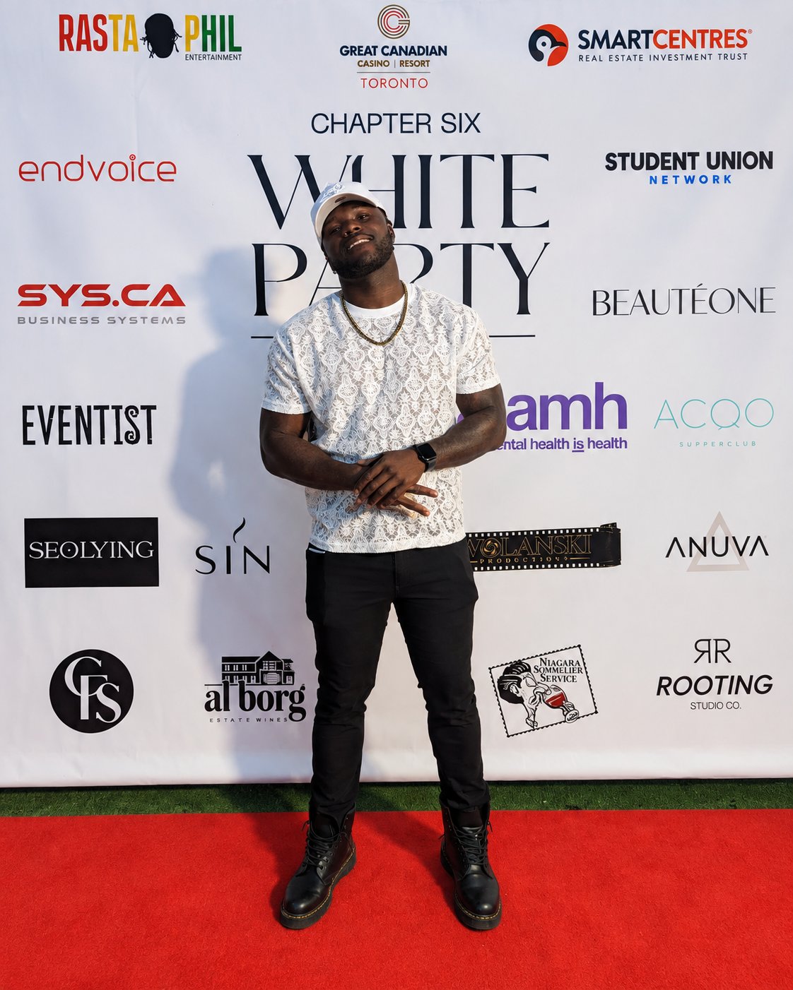 ELLI on the red carpet wearing a white patterned shirt and white cap